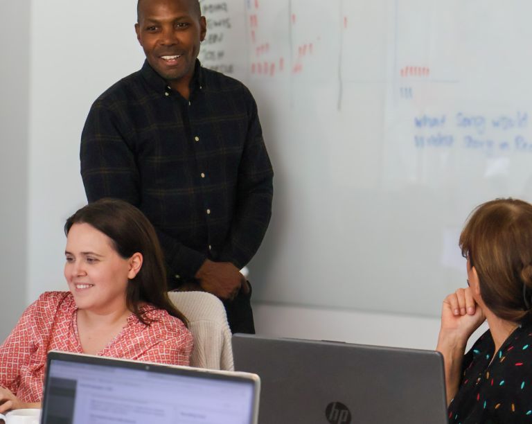 Signet Resources recruitment team engaged in a discussion around a table, with a whiteboard outlining key points in the background.