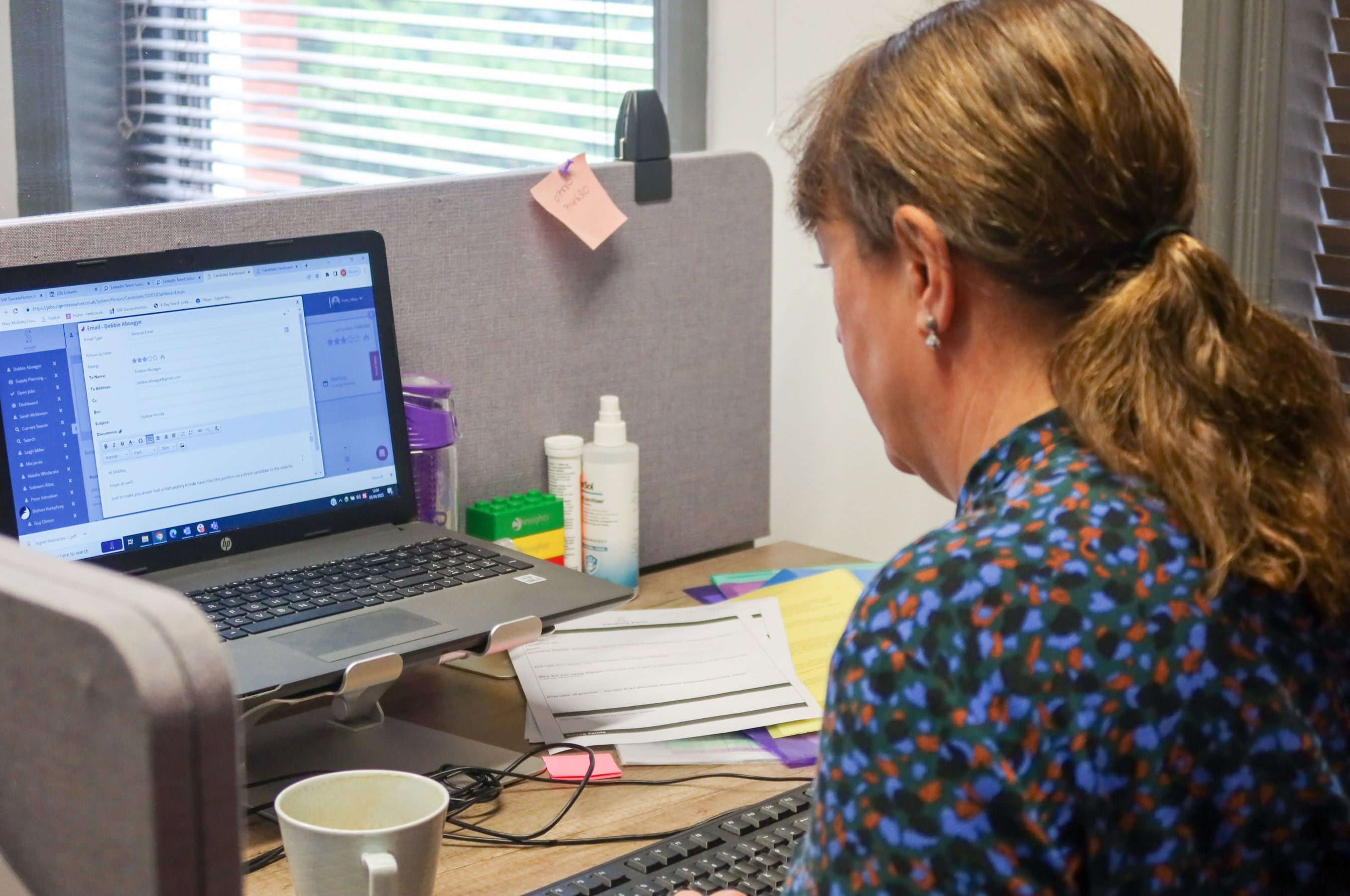 A Signet Recruitment and Retention employee working diligently on recruitment correspondences, immersed in the multitasking demands of her role.