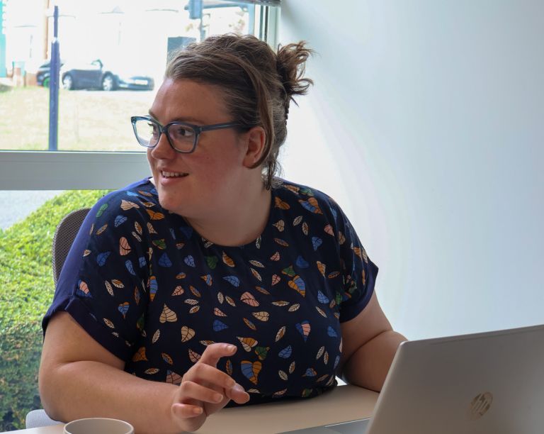 Signet Resources employee reviews recruitment data on a laptop while taking notes, highlighting a multitasking work environment.