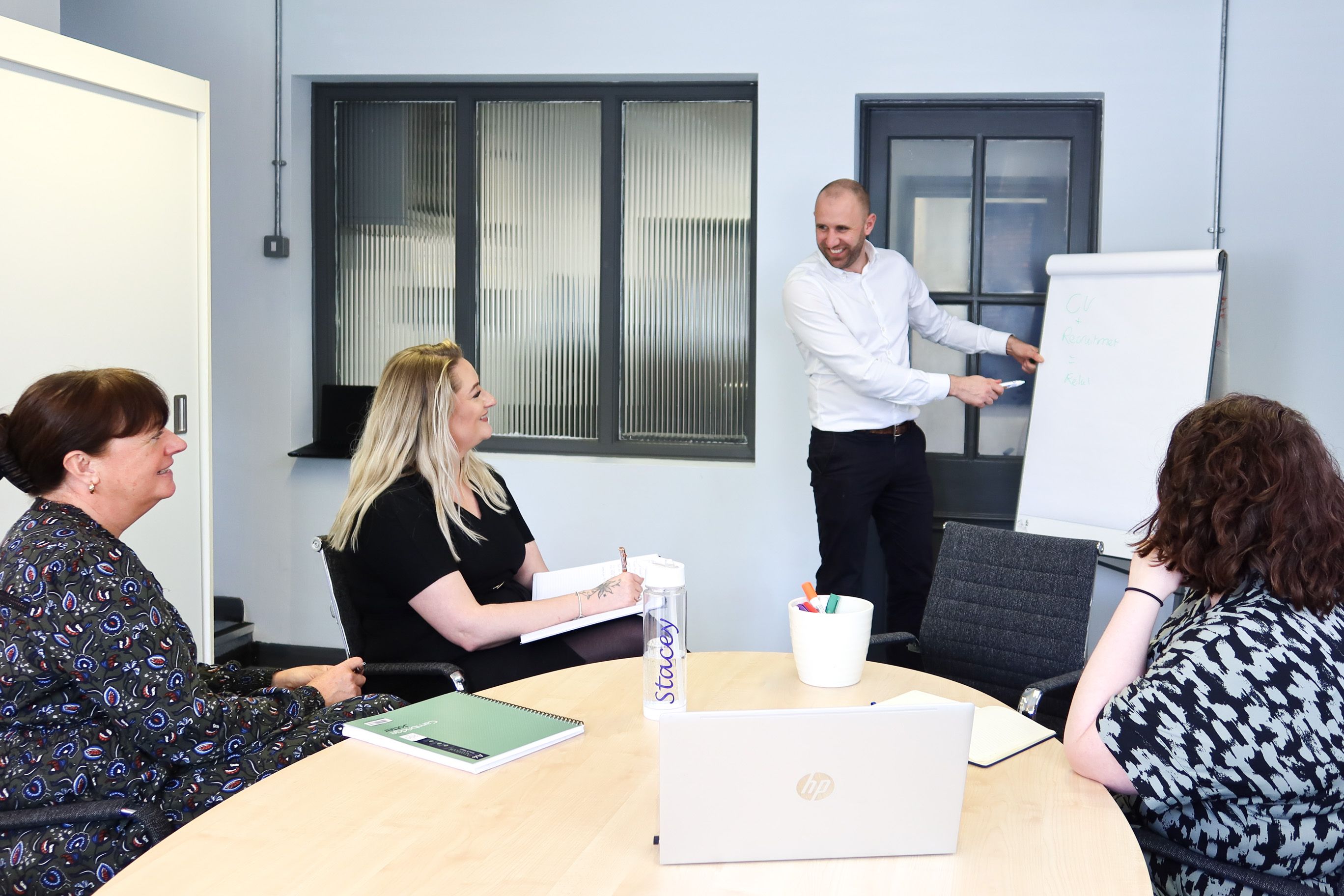 Signet Resources recruitment meeting in progress with a team member presenting CV strategies on a whiteboard to attentive colleagues.