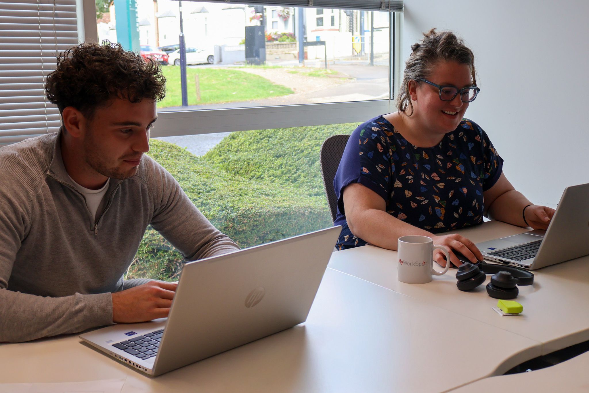 A Signet Resources team member shares insights from a notebook with a smiling colleague, enhancing their recruitment approach.