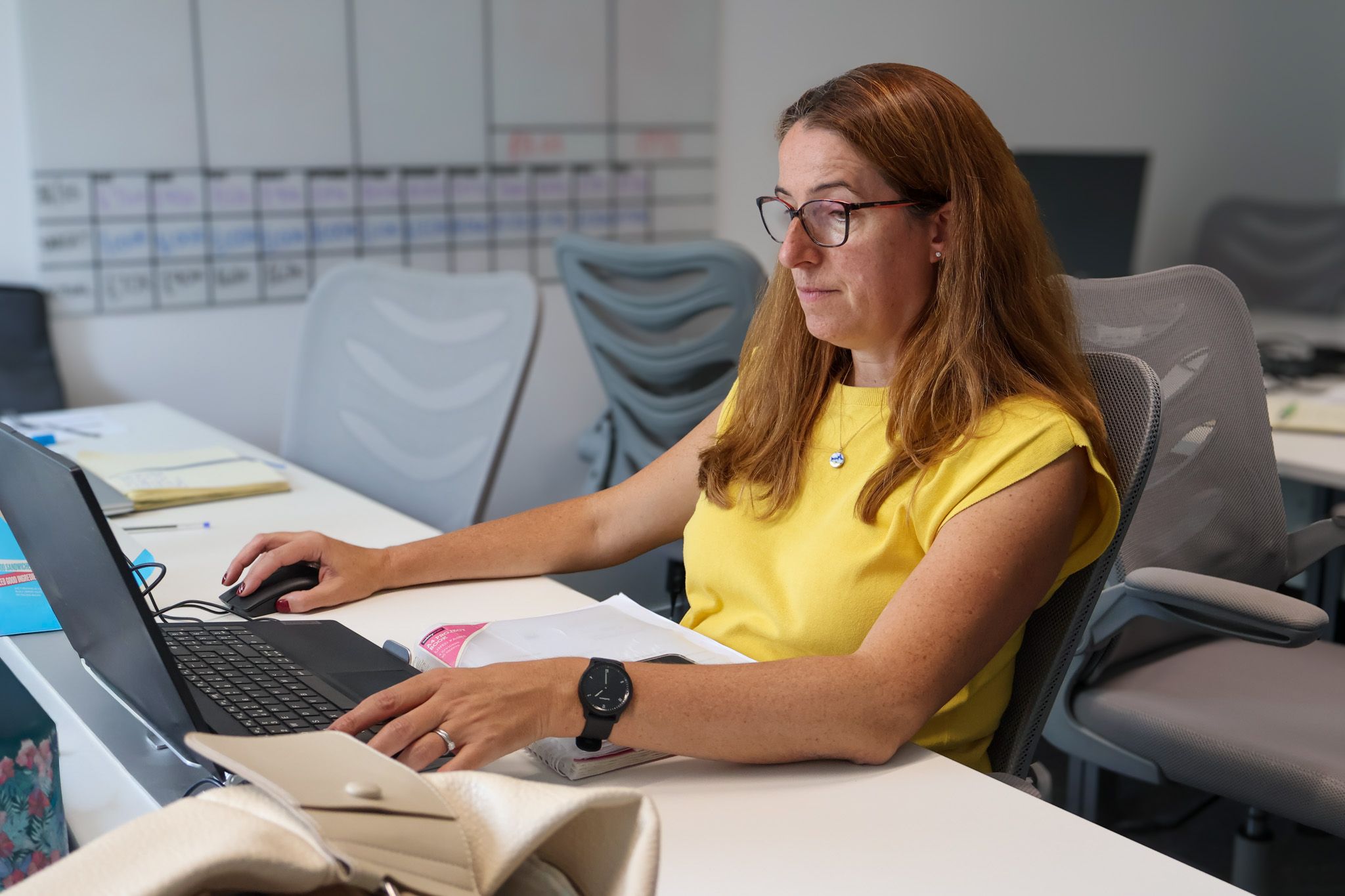 A dedicated Signet Resources staff member focused on recruitment planning, jotting down notes beside her laptop.