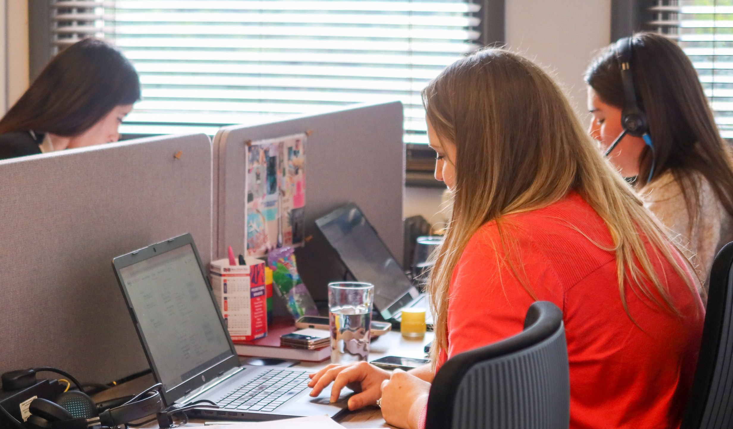 Busy Signet Resources office with staff focused on recruitment activities, using computers and headsets for efficient communication.