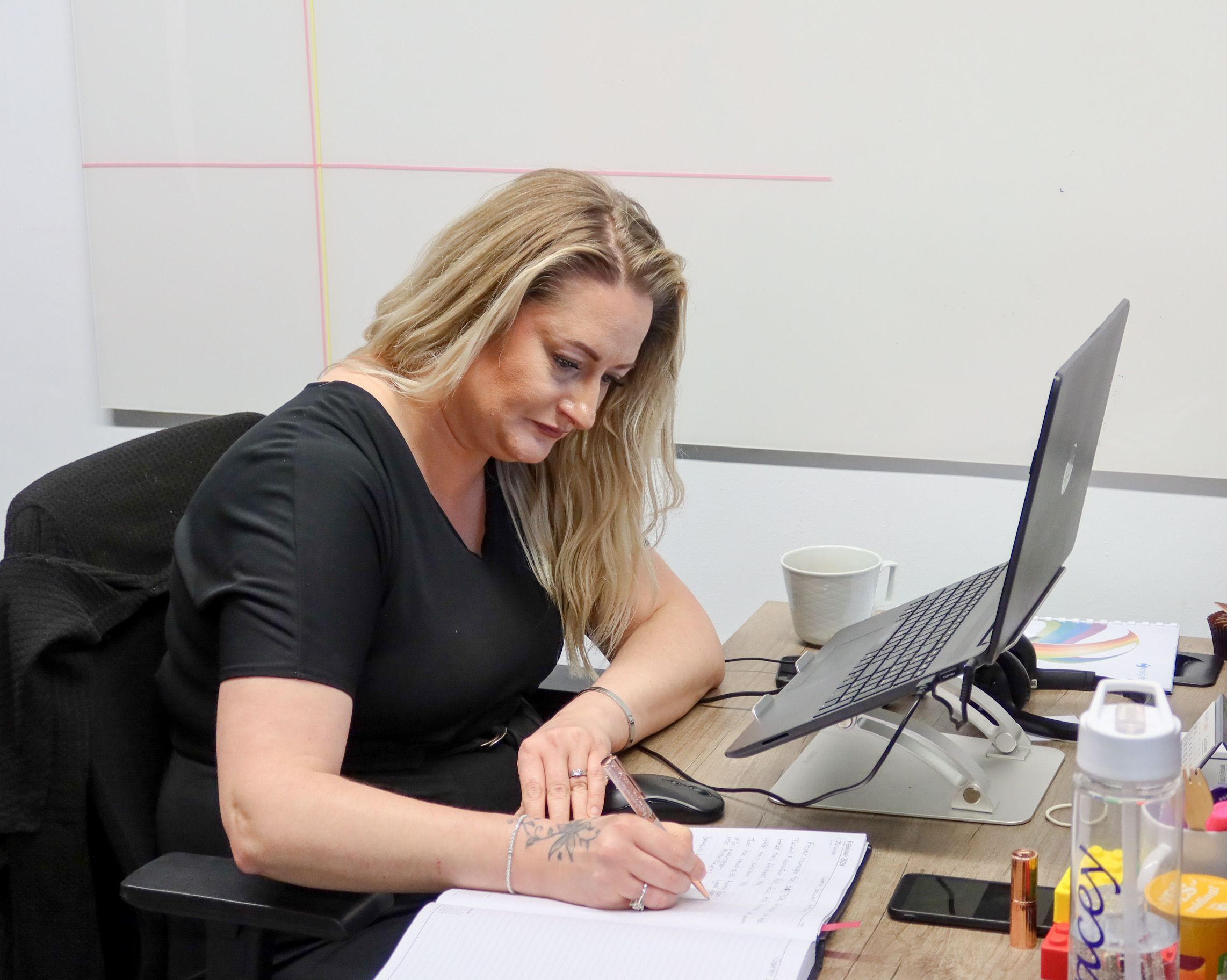 dedicated Signet Recruitment and Retention staff member focused on recruitment planning, jotting down notes beside her laptop.