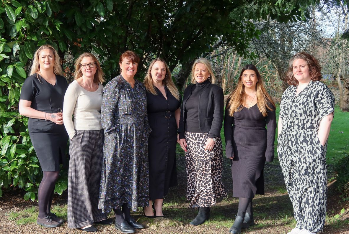 The Signet Recruitment and Retention team stands ready and professional amidst a natural setting, reflecting the team's cohesion and spirit.