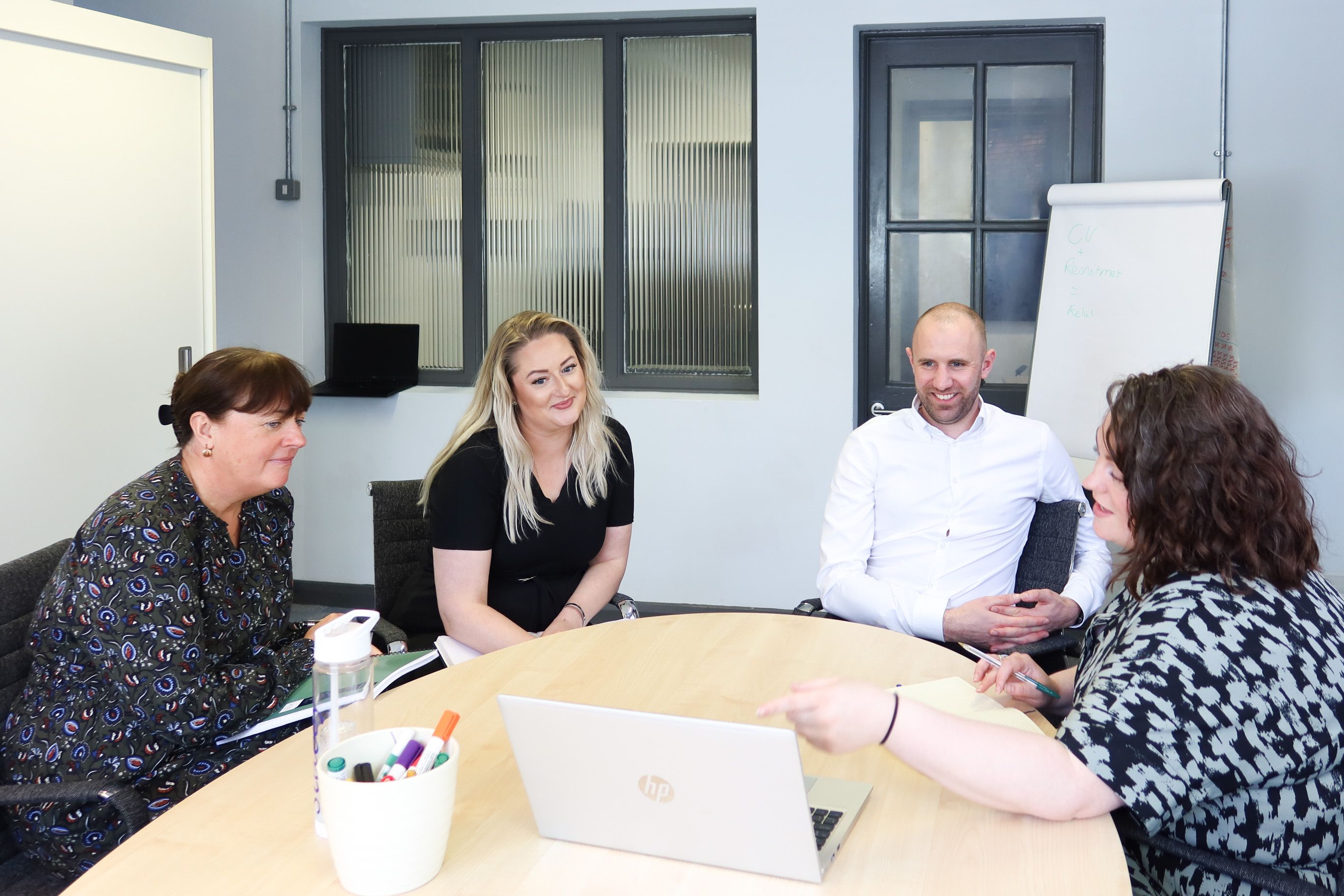 Signet Resources recruitment team engaged in a discussion around a table, with a whiteboard outlining key points in the background.