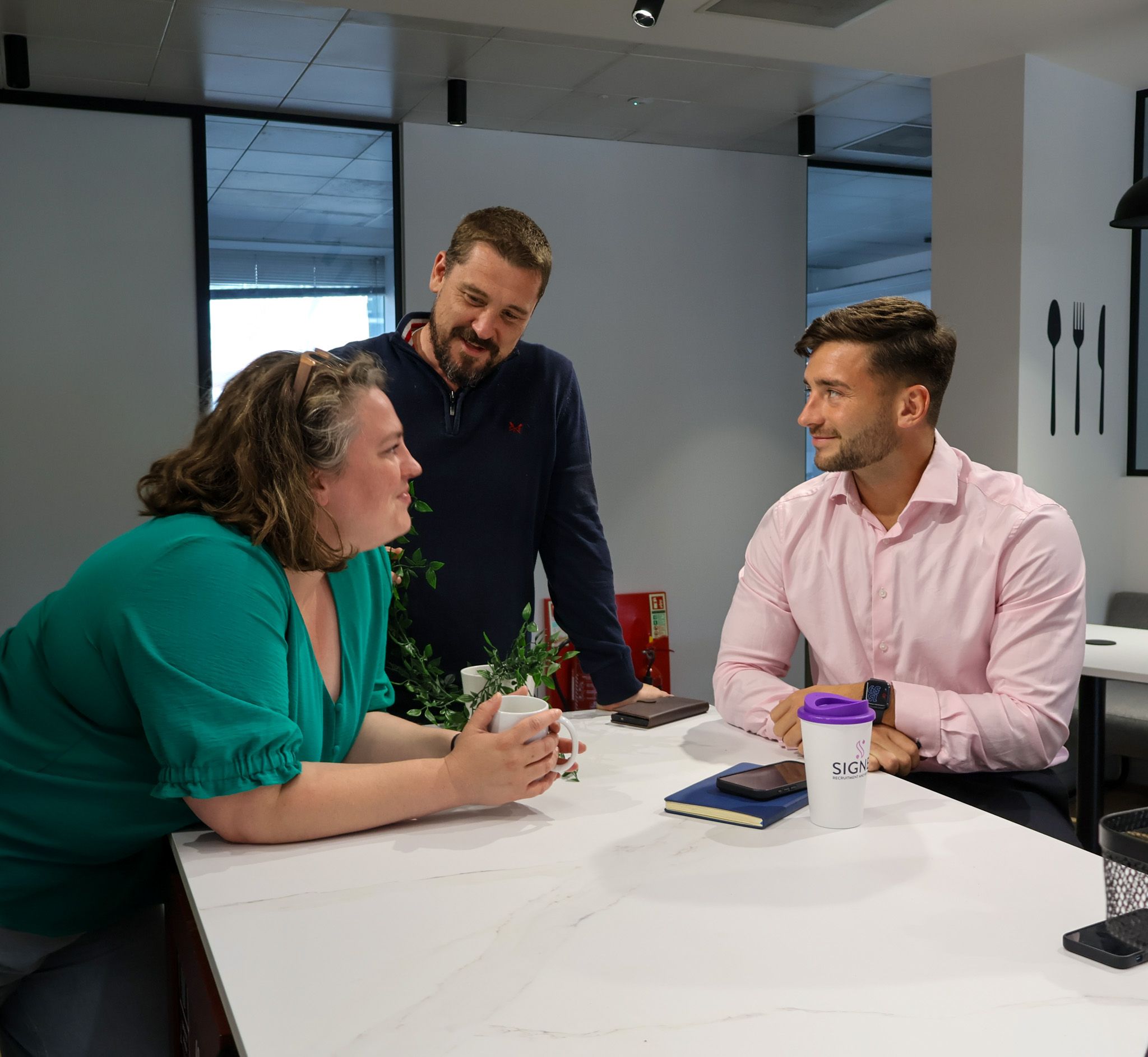 Busy Signet Resources office with staff focused on recruitment activities, using computers and headsets for efficient communication.