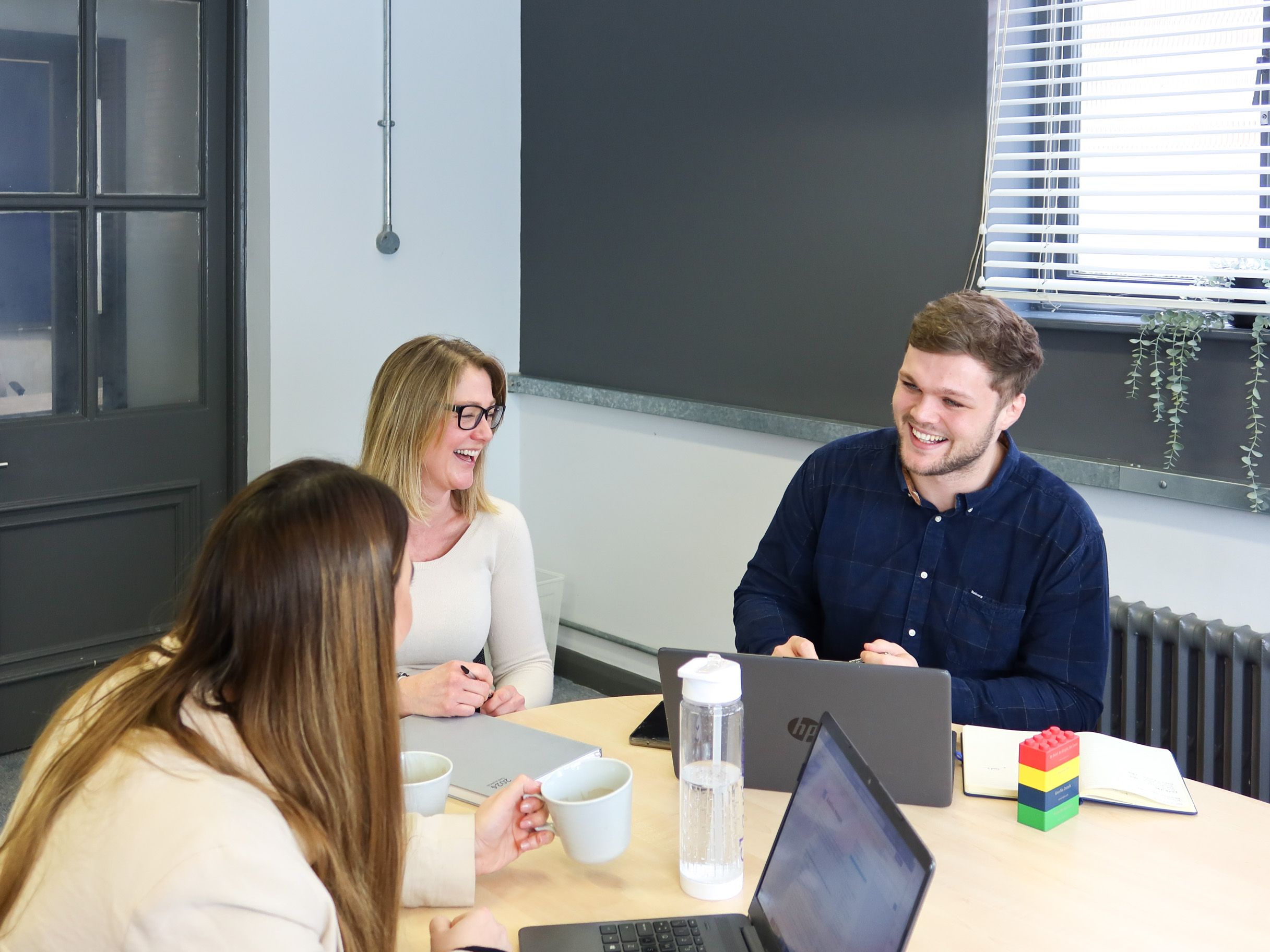 Three colleagues from Signet Resources enjoying a light-hearted moment during a recruitment strategy meeting.