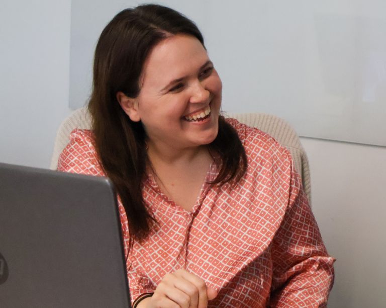 A Signet Resources team member shares insights from a notebook with a smiling colleague, enhancing their recruitment approach.