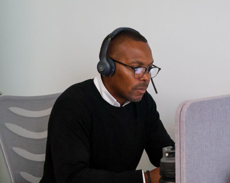 Signet Resources employee reviews recruitment data on a laptop while taking notes, highlighting a multitasking work environment.