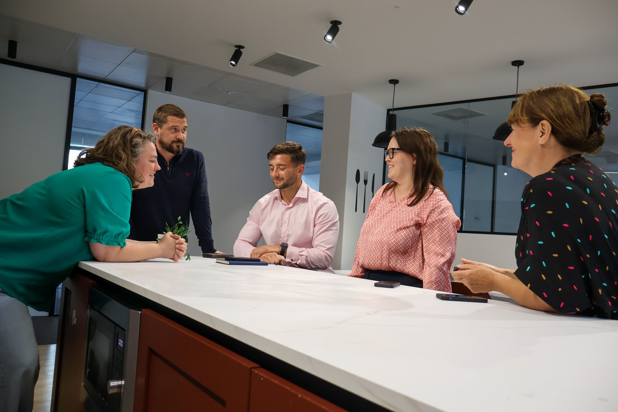 A Signet Resources team member shares insights from a notebook with a smiling colleague, enhancing their recruitment approach.