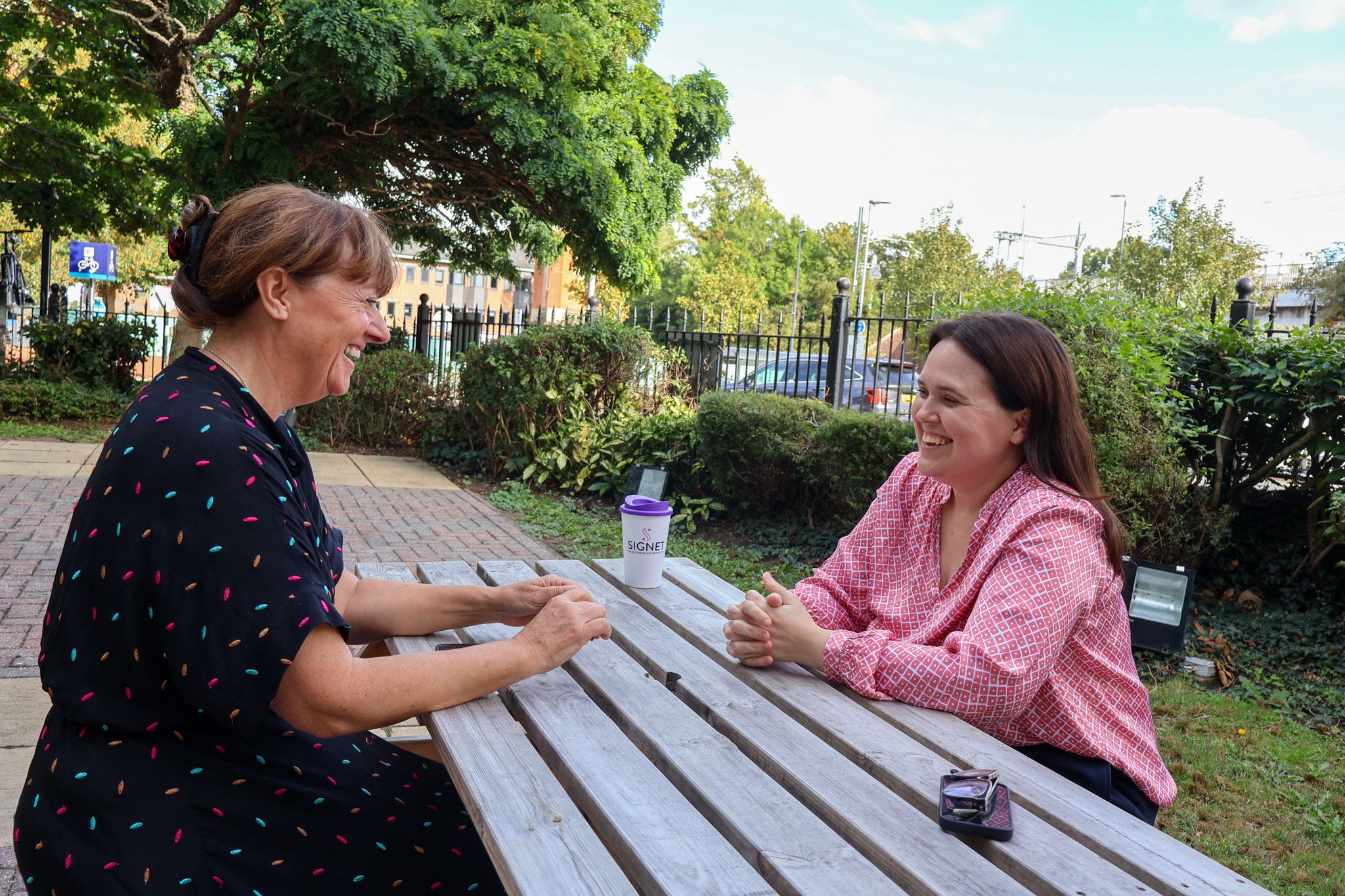 A Signet Resources team member shares insights from a notebook with a smiling colleague, enhancing their recruitment approach.