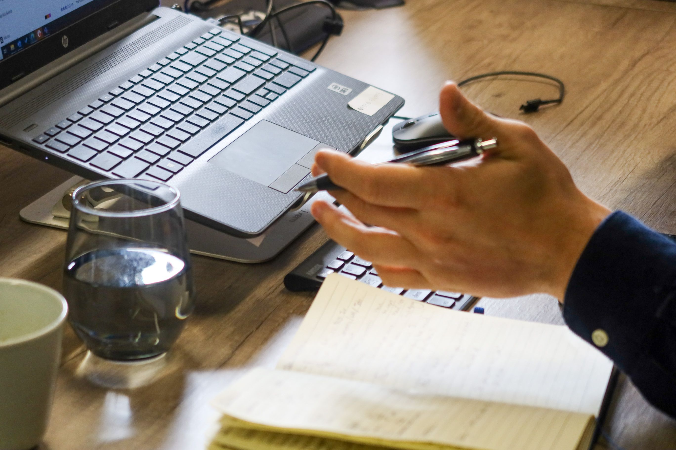 Signet Resources employee reviews recruitment data on a laptop while taking notes, highlighting a multitasking work environment.