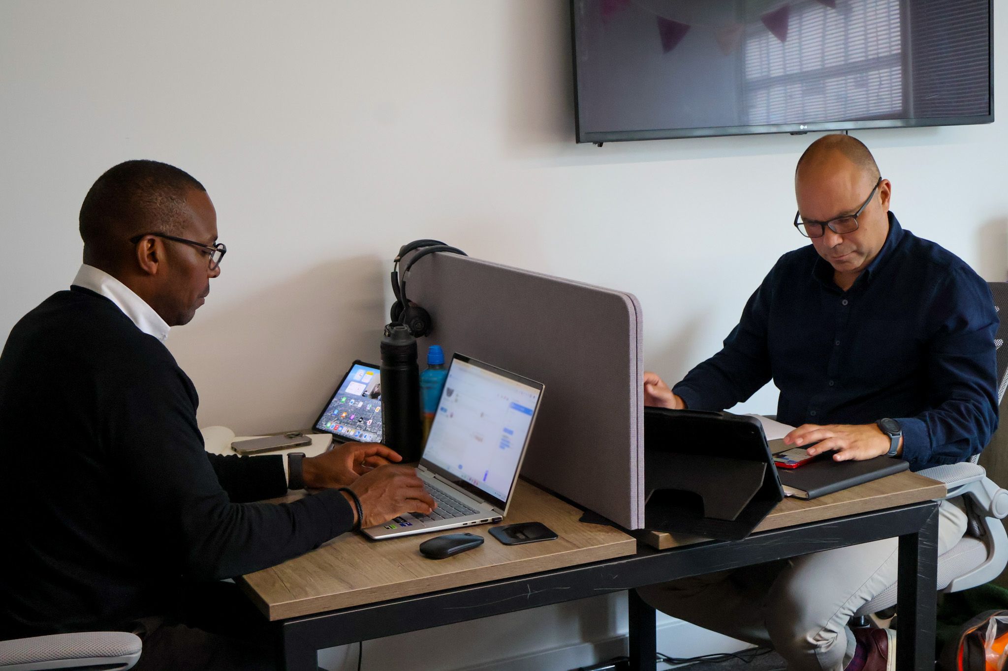 Signet Resources employee reviews recruitment data on a laptop while taking notes, highlighting a multitasking work environment.
