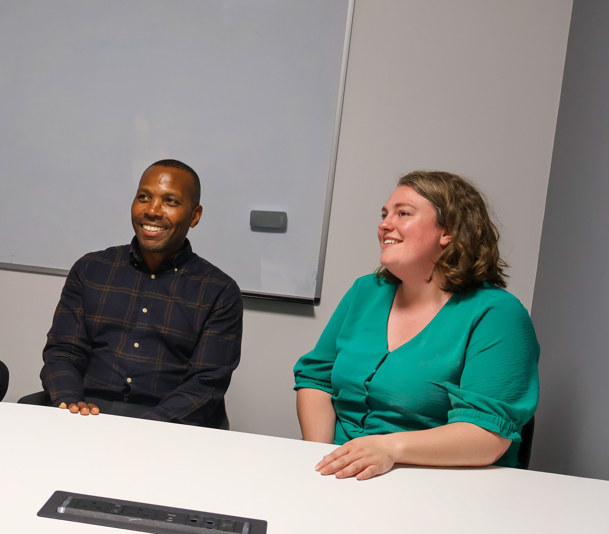 A Signet Resources team member shares insights from a notebook with a smiling colleague, enhancing their recruitment approach.