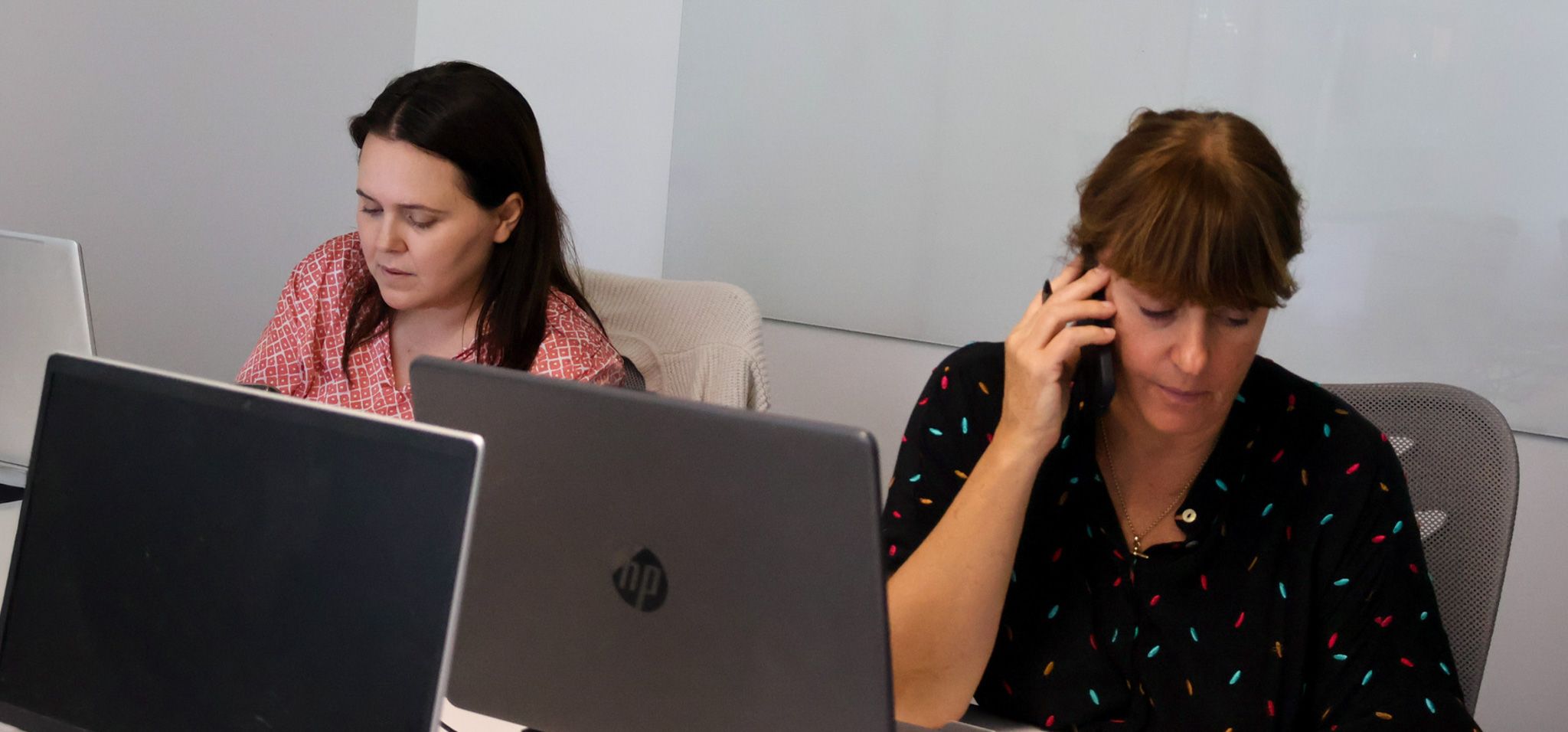 Signet Resources employee reviews recruitment data on a laptop while taking notes, highlighting a multitasking work environment.