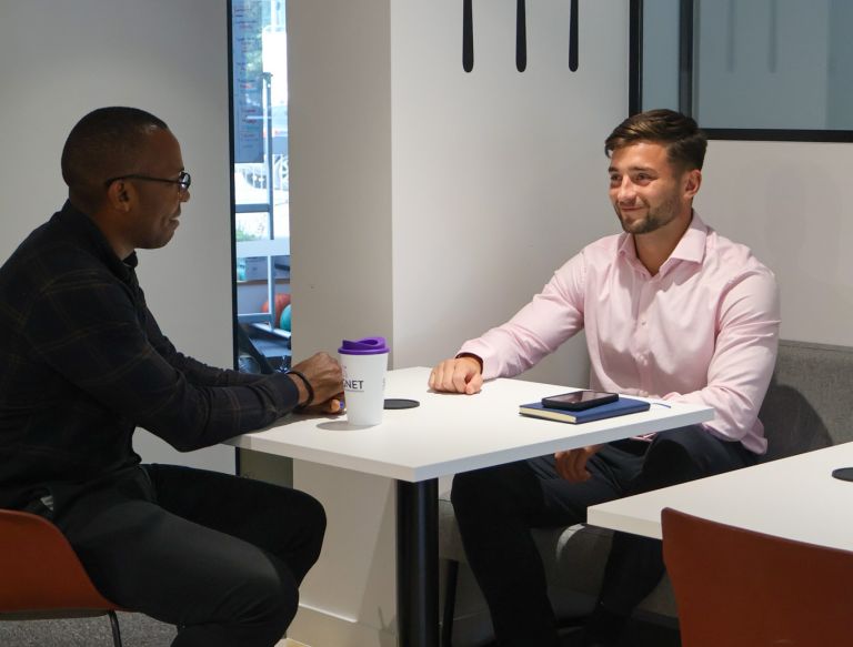 A Signet Resources team member shares insights from a notebook with a smiling colleague, enhancing their recruitment approach.