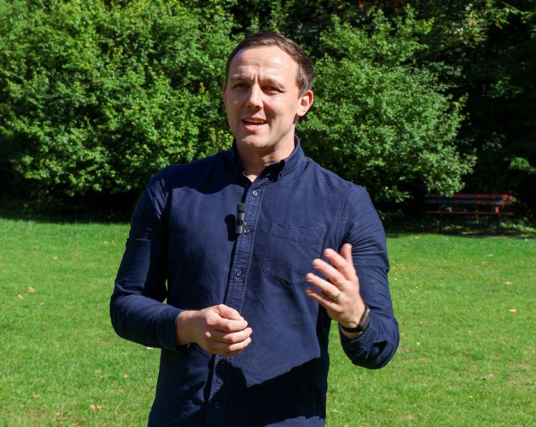 Signet Resources employee reviews recruitment data on a laptop while taking notes, highlighting a multitasking work environment.